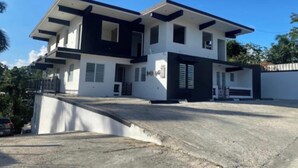 A modern two-story house with a flat roof, white exterior walls, and dark trim. - Pompeii Apartment (Aguada)