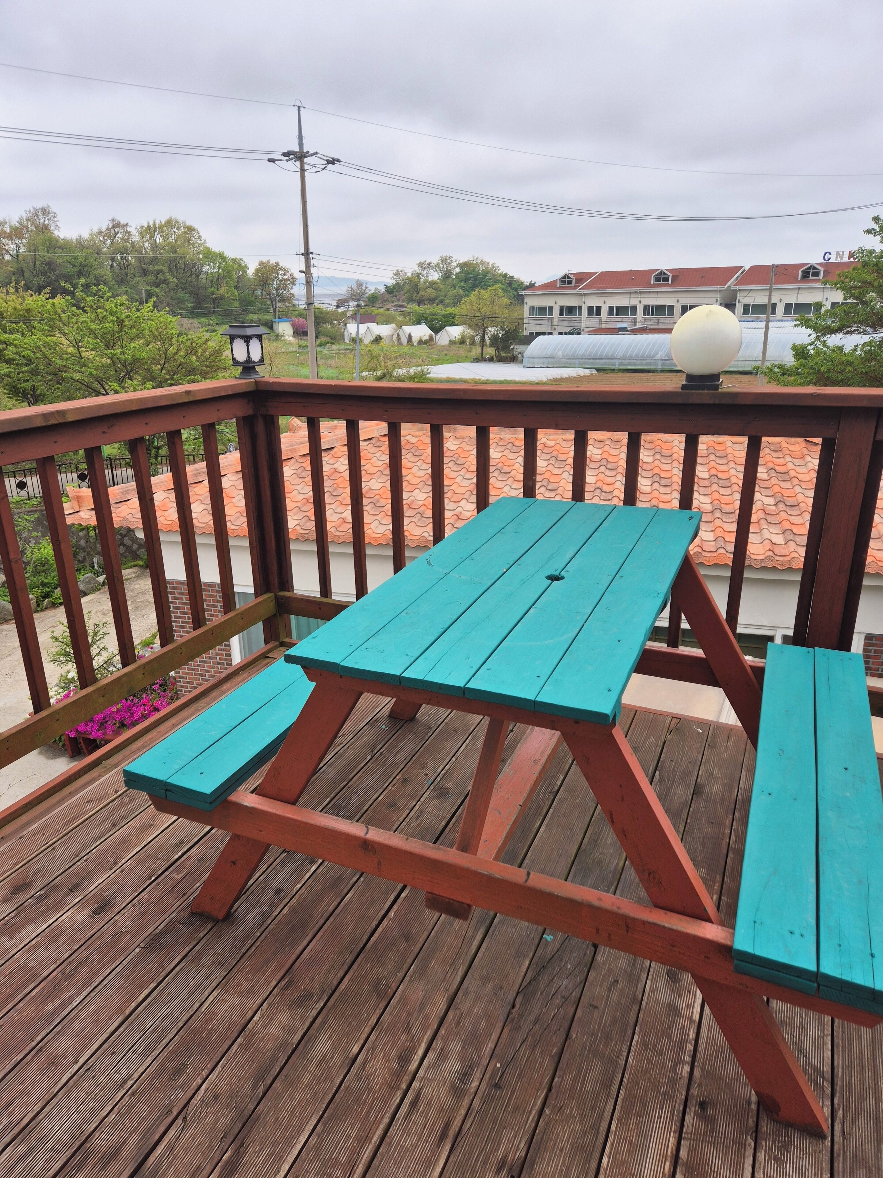 A wooden deck with a picnic table and benches, surrounded by a railing.