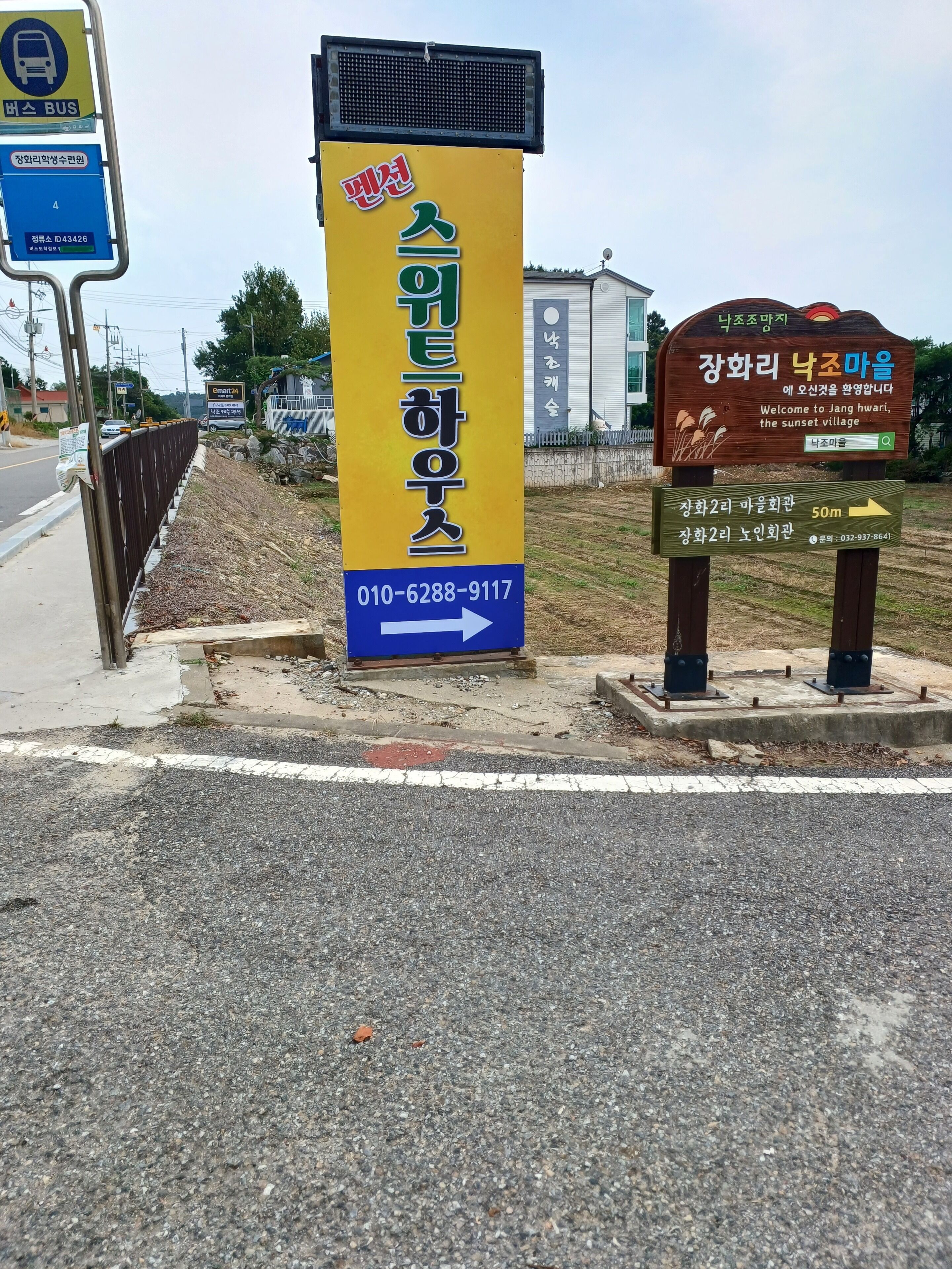 A bus stop sign with a contact number and directional arrows.