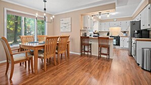 A spacious kitchen with wooden flooring, white cabinets, and a central island.