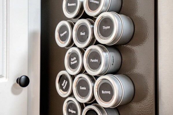 A row of spice jars with labels such as Rosemary, Cinnamon, Thyme, Basil, Parsley, Garlic Powder, Cumin, Nutmeg, and Oregano. - Large Luxurious 3/3 Lake Home
(Mount Ida)