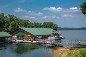 A lakeside cabin with a dock, a boat, and a small building with a green roof. - Large Luxurious 3/3 Lake Home
(Mount Ida)