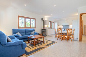 Un salon avec un canapé bleu, une table basse en bois et un coin repas comprenant des chaises et une table en bois.