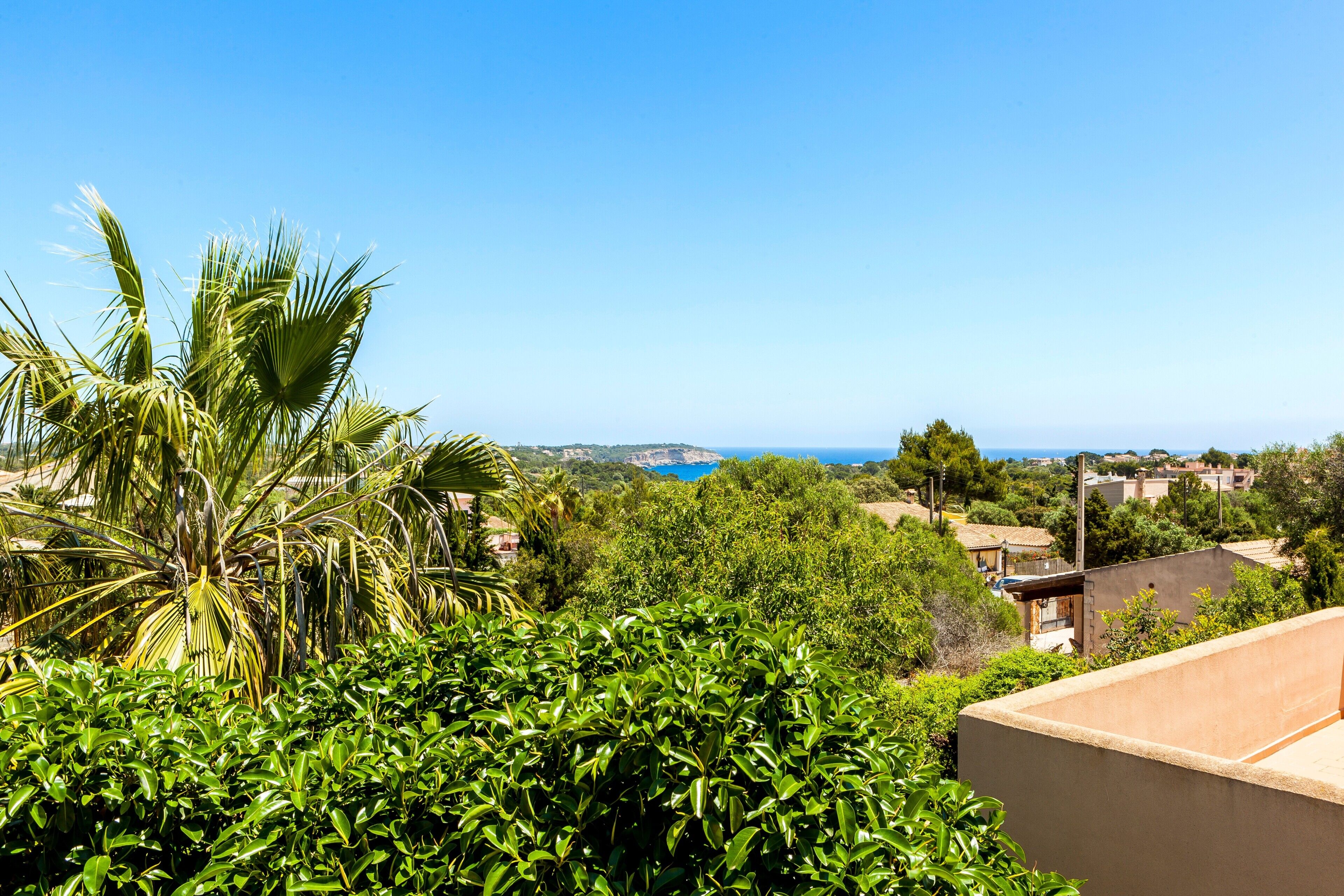 Ein Wohngebiet mit üppigem Grün, blauem Himmel und einem fernen Blick auf das Meer.
