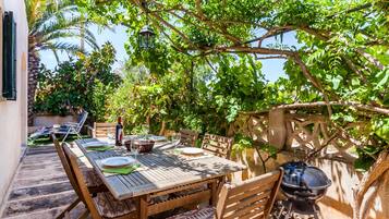 Un área de comedor al aire libre con una mesa de madera, sillas y una parrilla.