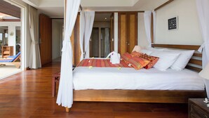 Ein geräumiges Schlafzimmer mit einem großen Bett, Holzbalken, einem Deckenventilator und Blick ins Freie.