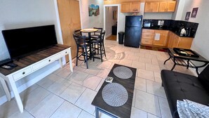 A compact living space with a dining area, kitchenette, and a TV on a stand. - Elegant Condo - European Charm (Palm Coast)
