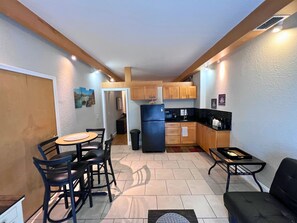Cozy living space with a kitchenette and dining area, featuring a round table and comfortable seating for four.