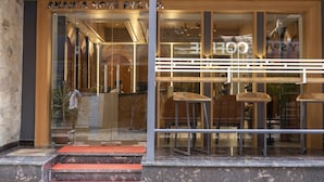 L’entrée d’un hôtel moderne, avec une façade en verre, des marches en bois et une rambarde en métal.