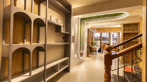 Un intérieur moderne avec un escalier en bois, un espace d’accueil et, au fond, un café.