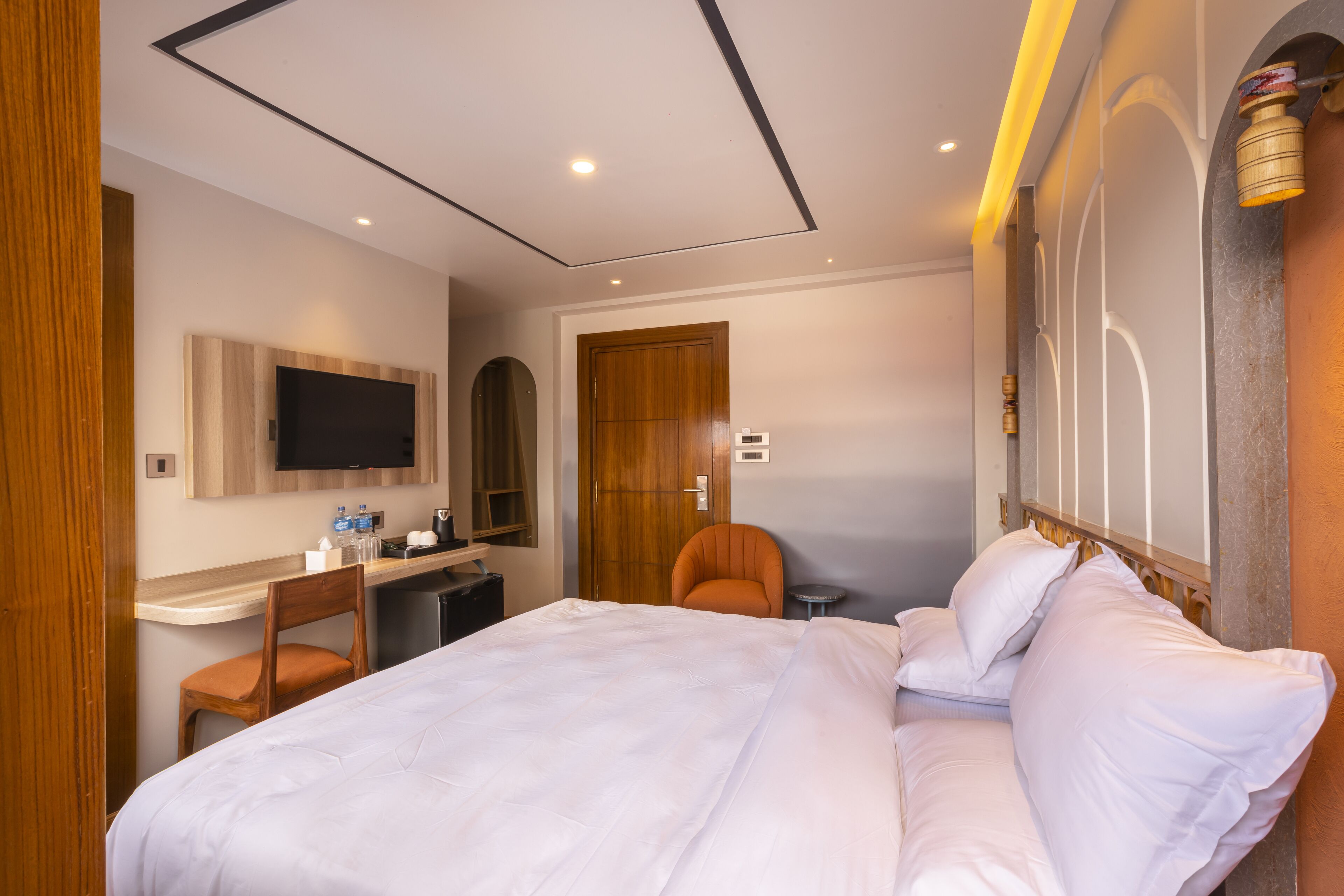 Ein Hotelzimmer mit Bett, Schreibtisch, Stuhl, Fernseher und einer Tür.