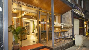 L’entrée d’un hôtel avec une façade en verre, un intérieur en bois et des places assises à l’extérieur.