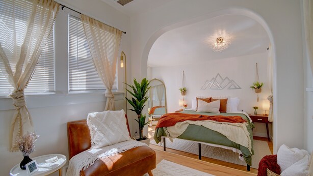 Une chambre à coucher avec un lit, une chaise, une petite table et une plante.