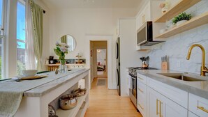 Une cuisine moderne avec des armoires blanches, un pare-feu en marbre et un plan de travail en bois.