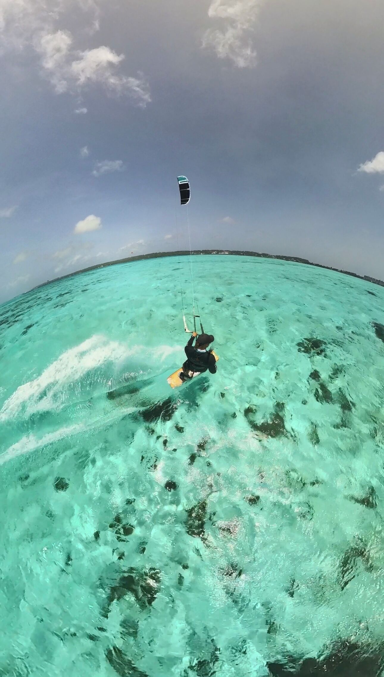 Una persona parapenteando sobre aguas turquesas con cielo despejado.
