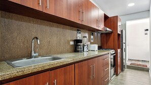 Une cuisine moderne dotée de plans de travail en granit, d’appareils électroménagers en acier inoxydable et d’armoires en bois.