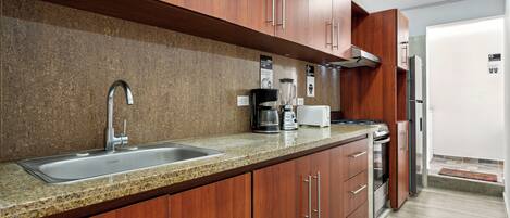 Eine moderne Küche mit Granit-Arbeitsplatten, Edelstahlgeräten und Holzschränken.