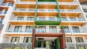 Et moderne hotel med flere etager, med altaner, en grøn taghave og en facade af sten.