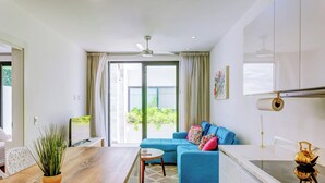 En moderne stue med en blå sofa, et træspisebord og et køkkenområde med en komfur.