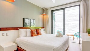 Et hotelværelse med seng, skrivebord, stol og balkon med udsigt.