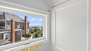 A room with a window overlooking a residential area and the sea.