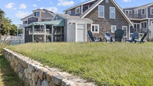 A residential area with houses, a covered outdoor seating area, and a stone wall.