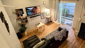 A modern living room with a sofa, a TV, a small table, and a window with curtains.