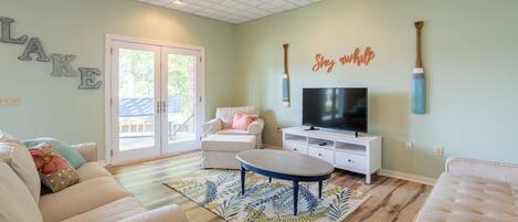 A living room with a television, a ceiling fan, and a large window.