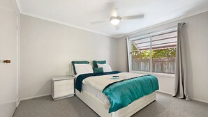Une chambre à coucher avec un lit, une table de chevet et un ventilateur de plafond.