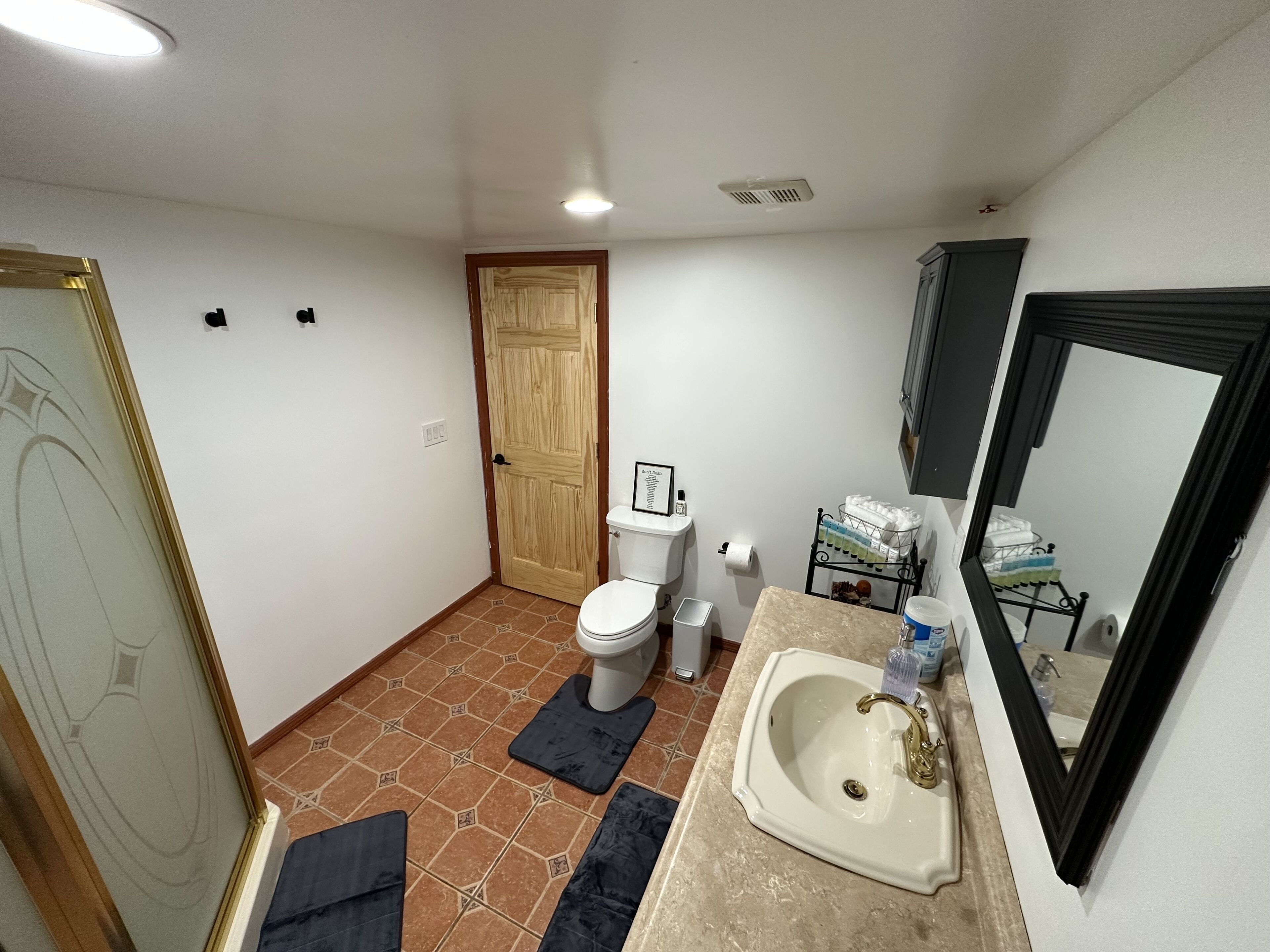 A bathroom with a toilet, sink, mirror, and a shower area.