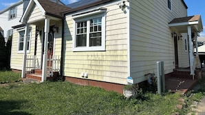 A two-story house with a front porch, a small front yard, and a solar panel on the roof.
