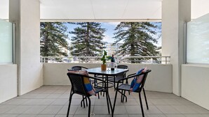 A balcony with a table and chairs, a bottle of wine, and a potted plant.