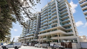 A multi-story residential building with balconies, a garage, and a parking area.