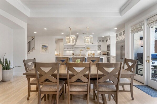 A modern kitchen with white cabinetry, a central island, and pendant lighting. - Brookside Birdie 5bd/4.5ba (Tulsa)