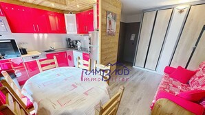 Un espace de vie compact comprenant une cuisine, un coin repas et une petite chambre.