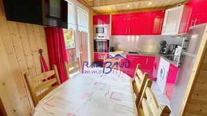Une cuisine avec des meubles de rangement rouges, un four à micro-ondes et un réfrigérateur.