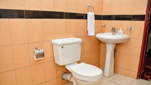 Une salle de bain équipée de toilettes, d’un lavabo et d’un porte-serviettes.