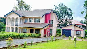 Une maison à deux étages, avec une façade rouge et beige, un garage et un jardin bien entretenu.