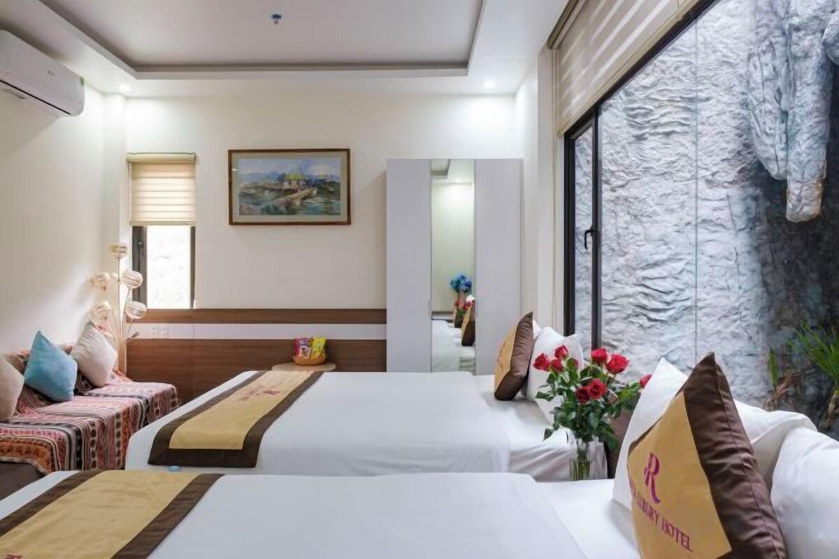 A hotel room with two beds, a large window, a painting on the wall, and a decorative wall feature.