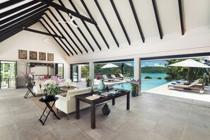 Un vaste espace de vie avec piscine, coin salon extérieur et vue sur un paysage tropical.