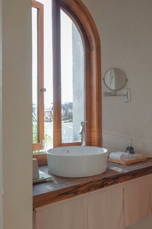 A bathroom with a large arched window, a white sink, a mirror, and a towel rack. - Nha Binh Homestay (Da Nang)
