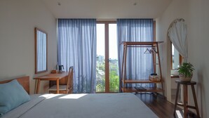 Een slaapkamer met een bed, een houten bureau, een stoel, een hangstoel en een potplant.