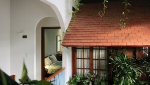 Een kamer met een dak van rode tegels, een houten deur en een bed met een groene deken.