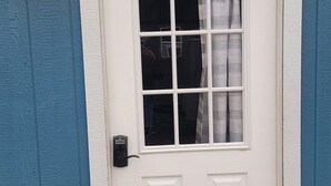 A white door with a window, a doorbell, and a wall-mounted light fixture. - Glacier Park <br>Rising Wolf Johnson Ranch RV and Cabins  (East Glacier Park)