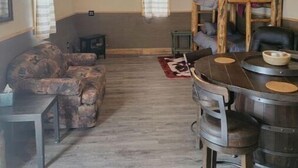 A rustic cabin interior with a dining area, a sofa, and a ceiling fan. - Glacier Park <br>Rising Wolf Johnson Ranch RV and Cabins  (East Glacier Park)