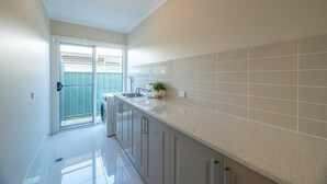Une cuisine avec des meubles blancs, un plan de travail et un revêtement mural en carreaux.