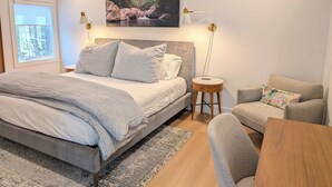 Makuuhuoneessa on suuri sänky, yöpöytä, tuoli, seinällä oleva taulu ja ikkuna.