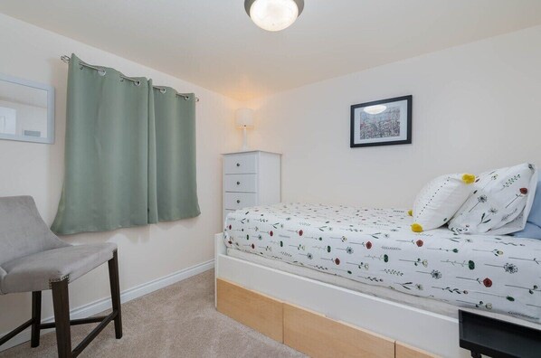 A bedroom with a bed, a chair, a bedside table, a lamp, and a framed picture on the wall. - Wallingford Oasis, comfortable home near everything (Seattle)