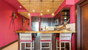 A modern kitchen with a central island, bar stools, and a wooden ceiling. - Luxury Condo with Panoramic Ocean Views, Sparkling Infinity Pool, and Modern Open-Concept Design (Playa Flamingo)