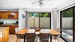 A dining area with a wooden table and chairs, a ceiling fan, and a view through large sliding glass doors. - Inviting Home with Colorful Decor and Private Backyard Oasis with a Swimming Pool & Shaded Terrace (Santa Cruz)